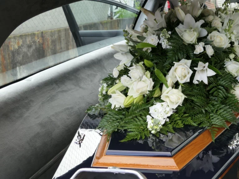 trumna z białymi kwiatami w samochodzie